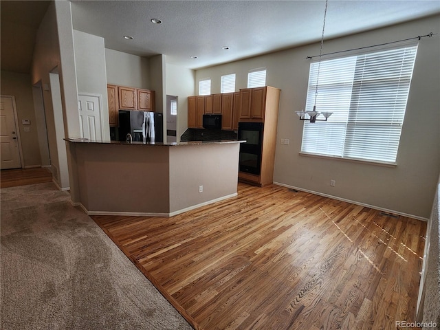 221 Homestead Pkwy, Longmont, CO 80504 - kitchen with black appliances, a peninsula, light wood finished floors, pendant lighting, and recessed lighting