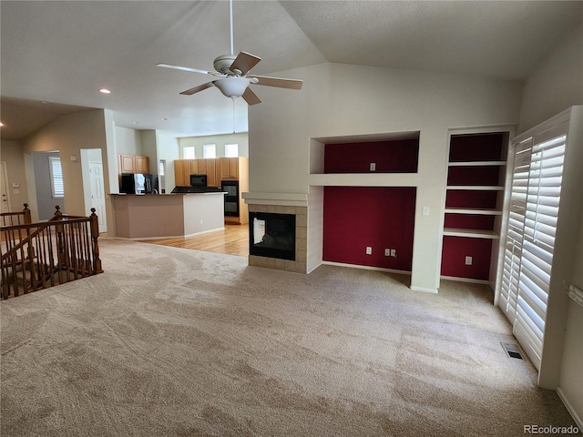 221 Homestead Pkwy, Longmont, CO 80504 - unfurnished living room featuring vaulted ceiling, light colored carpet, plenty of natural light, ceiling fan, and a tile fireplace