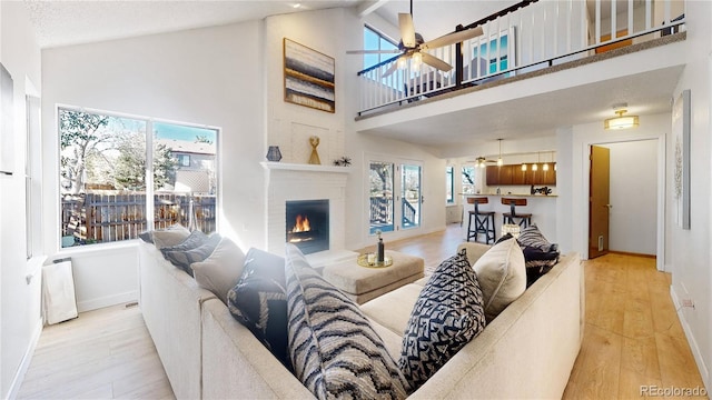 living room featuring light wood-type flooring, high vaulted ceiling, and a healthy amount of sunlight