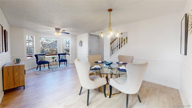 dining area featuring ceiling fan with notable chandelier, a textured ceiling, and light hardwood / wood-style flooring