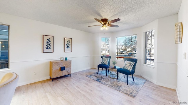 living area featuring a textured ceiling, light hardwood / wood-style flooring, and ceiling fan