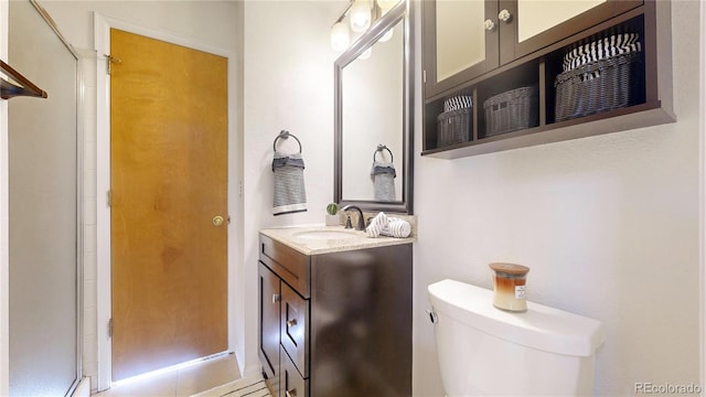 bathroom with tile patterned floors, vanity, a shower with shower door, and toilet