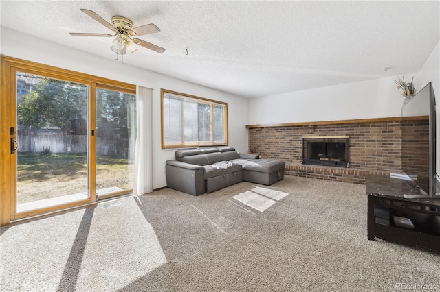 living room featuring light carpet, ceiling fan, a fireplace, and a textured ceiling