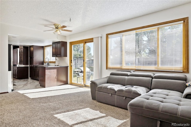 living room featuring a textured ceiling, light carpet, ceiling fan, and sink