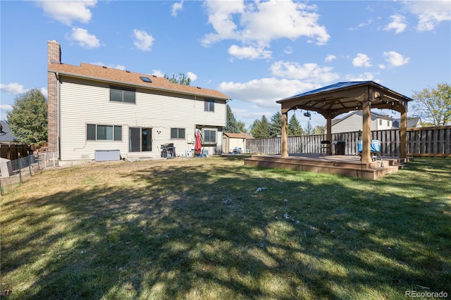 back of property featuring a wooden deck, a gazebo, and a yard