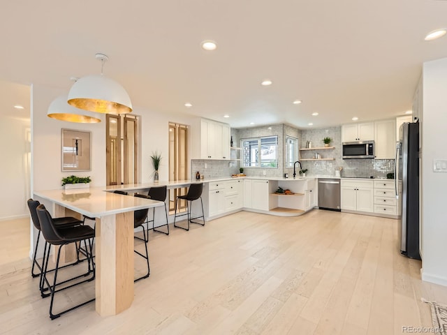 kitchen with appliances with stainless steel finishes, a peninsula, a kitchen breakfast bar, and tasteful backsplash