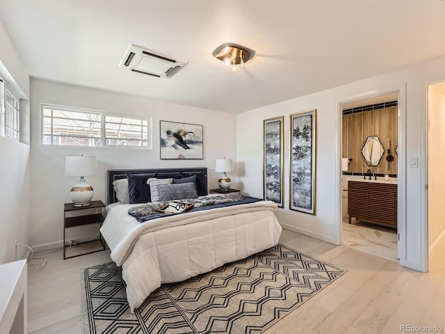 bedroom featuring light wood-style floors, baseboards, and an AC wall unit