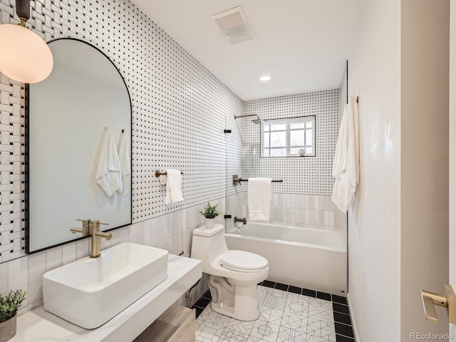 bathroom featuring bathing tub / shower combination, tile walls, toilet, a sink, and tile patterned floors