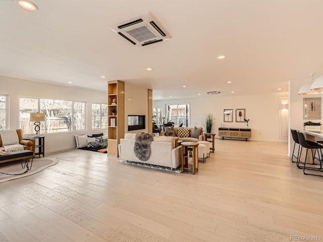 living area featuring light wood-style floors, baseboards, visible vents, and recessed lighting