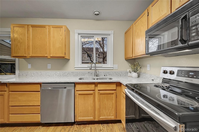 12028 W Aqueduct Dr, Littleton, CO 80127 - kitchen featuring light wood-style floors, appliances with stainless steel finishes, a sink, and light stone counters