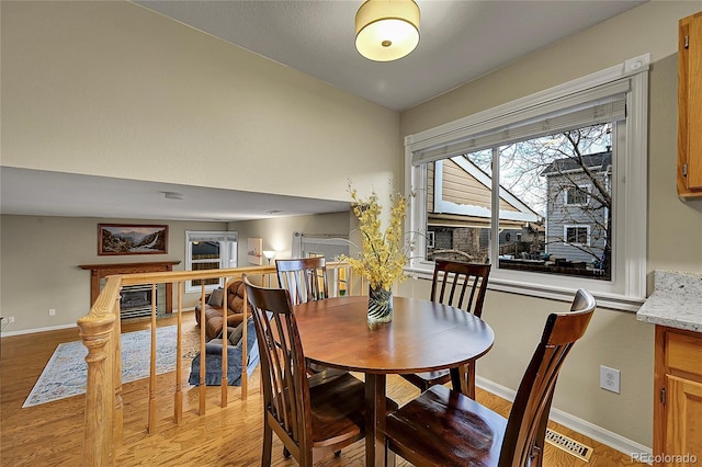 12028 W Aqueduct Dr, Littleton, CO 80127 - dining area with a tile fireplace, light wood finished floors, baseboards, and vaulted ceiling