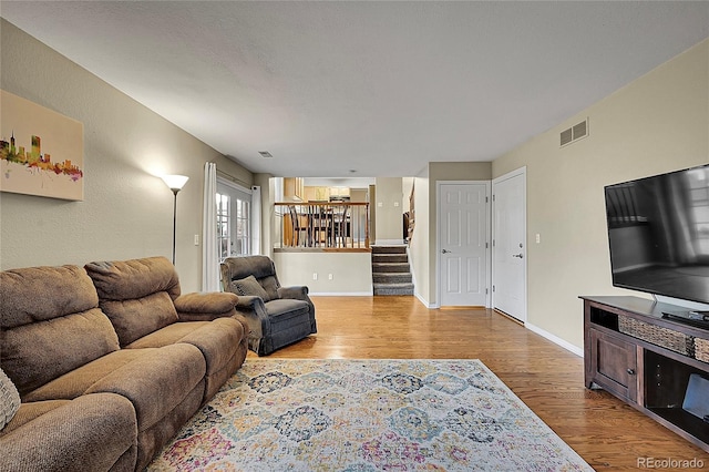 12028 W Aqueduct Dr, Littleton, CO 80127 - living area with wood finished floors, baseboards, visible vents, and stairs