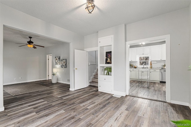 225 N Cedar St, Colorado Springs, CO 80903 - unfurnished living room with a textured ceiling, a ceiling fan, stairs, a sink, and wood finished floors
