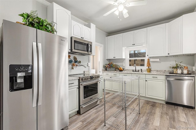 225 N Cedar St, Colorado Springs, CO 80903 - kitchen with appliances with stainless steel finishes, a ceiling fan, light wood-style floors, white cabinetry, and light stone countertops