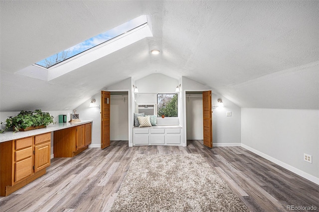 225 N Cedar St, Colorado Springs, CO 80903 - additional living space featuring vaulted ceiling with skylight, light wood-style floors, a textured ceiling, and baseboards