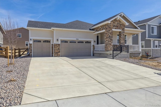 craftsman inspired home featuring fence, covered porch, concrete driveway, a garage, and stone siding