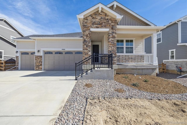 craftsman-style home with stone siding, covered porch, board and batten siding, concrete driveway, and an attached garage