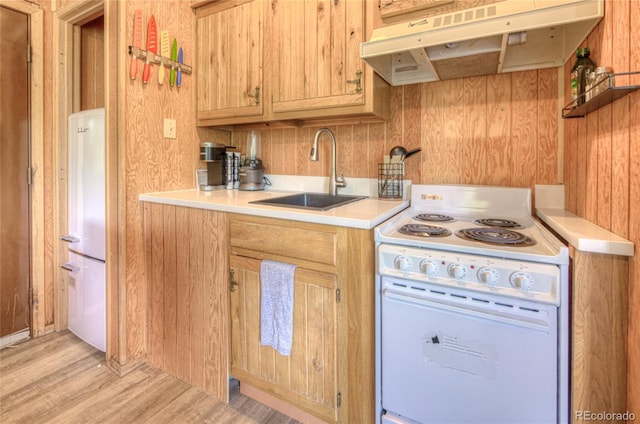 kitchen featuring light countertops, white appliances, under cabinet range hood, a sink, and light wood-style floors