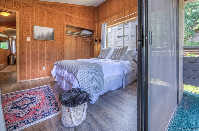 bedroom with wood walls, multiple windows, and wood finished floors