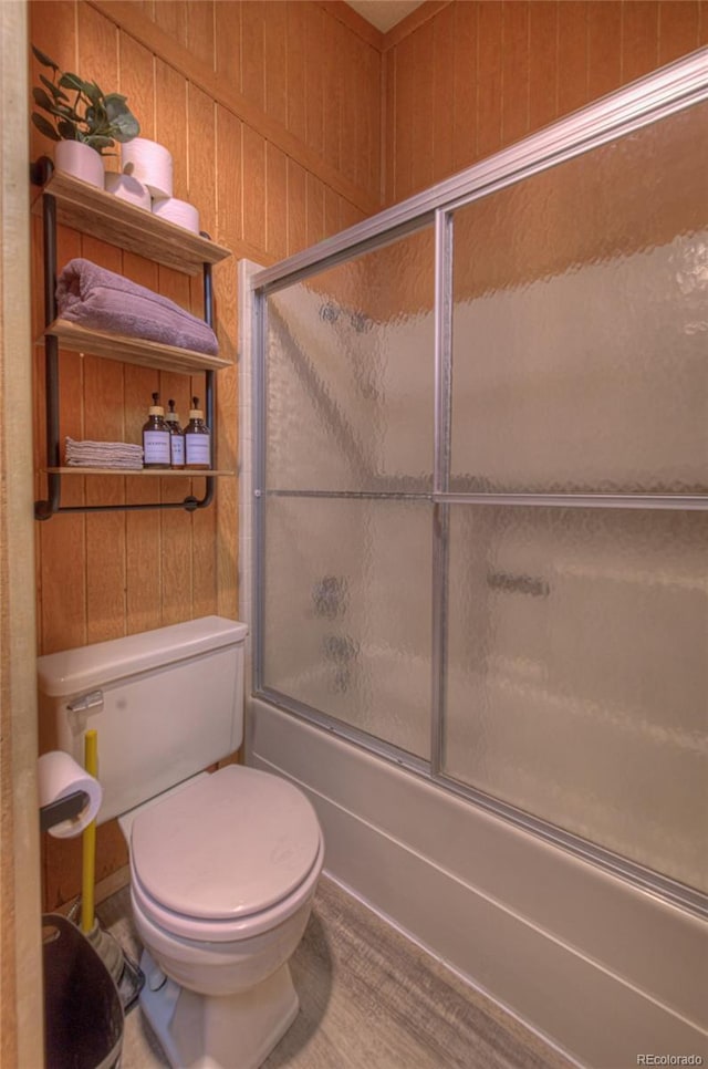 bathroom with toilet and shower / bath combination with glass door