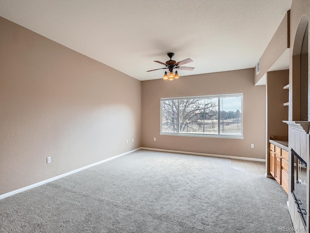 unfurnished living room with ceiling fan, light colored carpet, and a textured ceiling