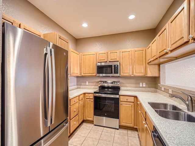 kitchen with appliances with stainless steel finishes, sink, light tile patterned floors, and light brown cabinetry