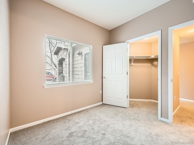 unfurnished bedroom featuring a spacious closet, light colored carpet, and a closet