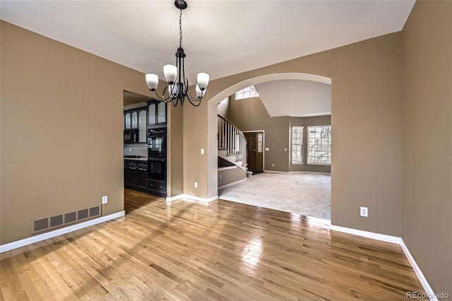 518 Zircon Way, Superior, CO 80027 - unfurnished room with arched walkways, baseboards, light wood-style floors, a chandelier, and stairway