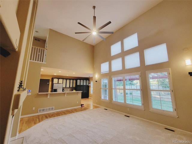 518 Zircon Way, Superior, CO 80027 - unfurnished living room featuring ceiling fan, baseboards, a high ceiling, light colored carpet, and light wood-type flooring