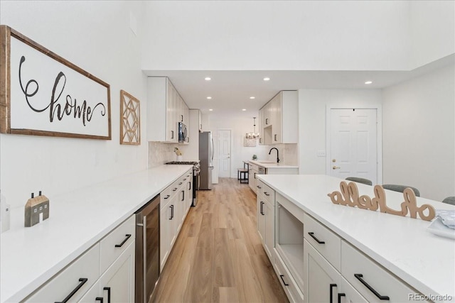 3413 W 114th Cir Unit B, Westminster, CO 80031 - kitchen with beverage cooler, stainless steel appliances, light wood-style flooring, recessed lighting, and white cabinetry