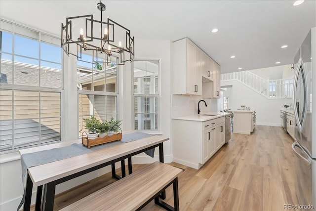 3413 W 114th Cir Unit B, Westminster, CO 80031 - kitchen featuring a chandelier, freestanding refrigerator, light wood finished floors, light countertops, and white cabinetry