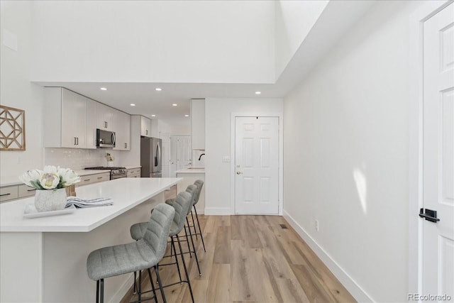 3413 W 114th Cir Unit B, Westminster, CO 80031 - kitchen with stainless steel appliances, a breakfast bar area, light wood-type flooring, light countertops, and recessed lighting