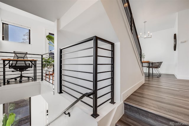 stairs featuring an inviting chandelier, baseboards, and wood finished floors