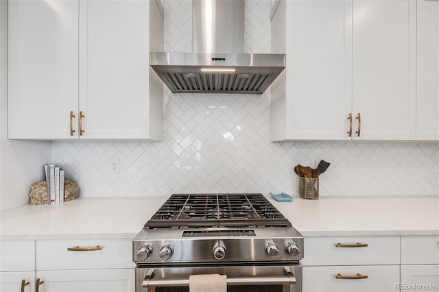 kitchen with white cabinetry, wall chimney range hood, high end stainless steel range oven, backsplash, and light stone countertops