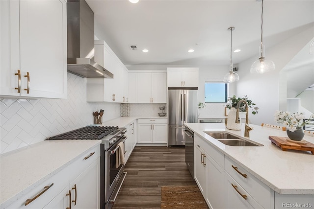 kitchen with stainless steel appliances, backsplash, white cabinets, a sink, and wall chimney exhaust hood