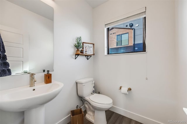 bathroom with toilet, baseboards, a sink, and wood finished floors