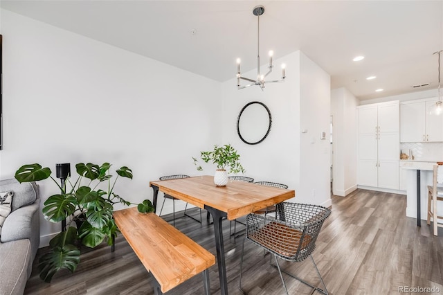 dining space with a chandelier, recessed lighting, baseboards, and wood finished floors