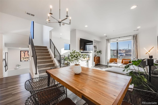 dining area featuring recessed lighting, visible vents, stairway, an inviting chandelier, and wood finished floors