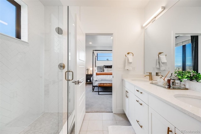 ensuite bathroom featuring double vanity, connected bathroom, a shower stall, a sink, and tile patterned floors