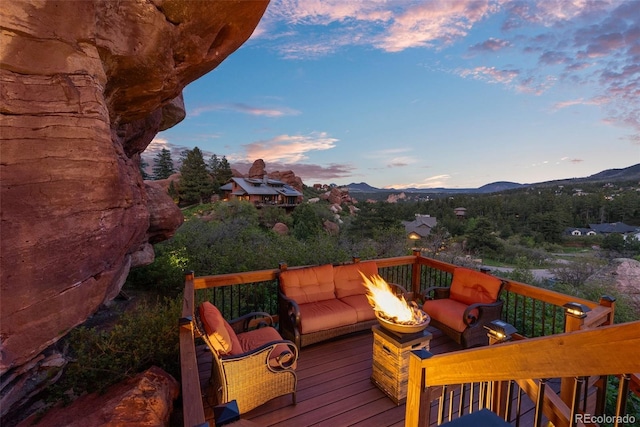 6619 Apache Pl, Larkspur, CO 80118 - deck at dusk featuring an outdoor living space with a fire pit and a mountain view
