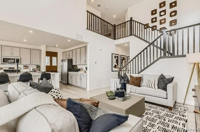 16947 W 92nd Dr, Arvada, CO 80007 - living area featuring light wood-style floors, stairway, a towering ceiling, recessed lighting, and baseboards