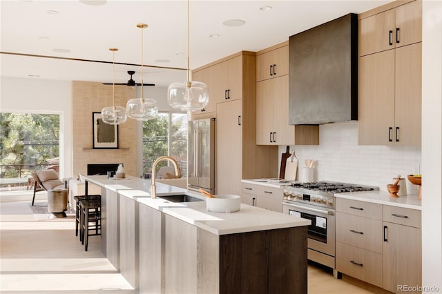 kitchen with a kitchen island with sink, high quality appliances, plenty of natural light, sink, and hanging light fixtures