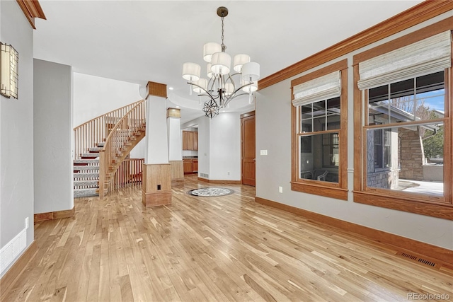 interior space featuring a notable chandelier, ornamental molding, and light hardwood / wood-style flooring