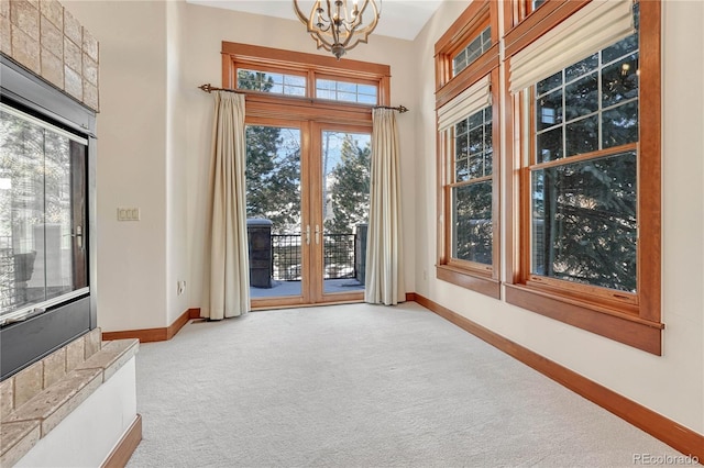 interior space featuring a healthy amount of sunlight, light colored carpet, and an inviting chandelier