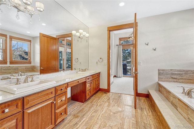 bathroom with vanity, a chandelier, and a relaxing tiled tub