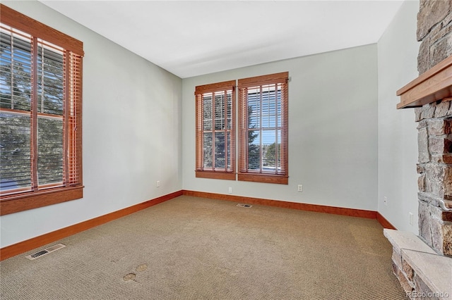 carpeted empty room with a fireplace