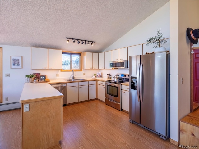 30455 Mountainside Dr, Buena Vista, CO 81211 - kitchen with appliances with stainless steel finishes, a sink, a textured ceiling, light wood-style floors, and a peninsula