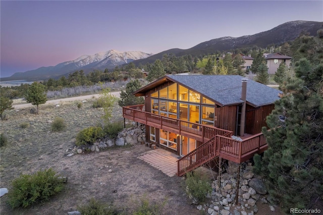 30455 Mountainside Dr, Buena Vista, CO 81211 - back of property at dusk featuring a deck with mountain view, stairs, roof with shingles, and a patio
