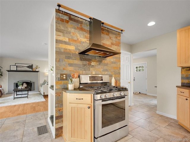 312 Allen St, Golden, CO 80401 - kitchen with stainless steel gas stove, island exhaust hood, light brown cabinetry, tasteful backsplash, and dark countertops