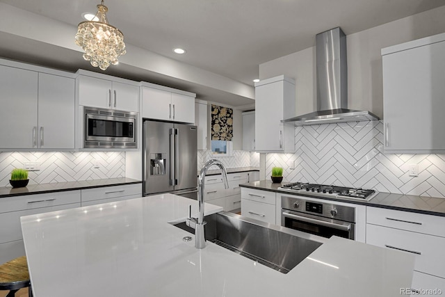 kitchen featuring white cabinetry, wall chimney exhaust hood, stainless steel appliances, backsplash, and pendant lighting